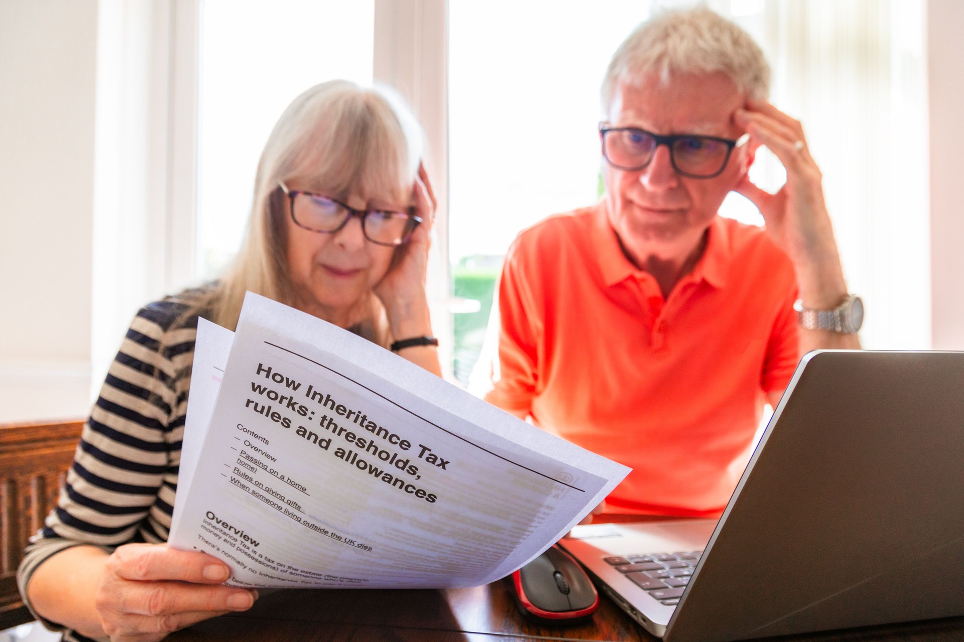 Worried senior couple looking at inheritance tax documents at home